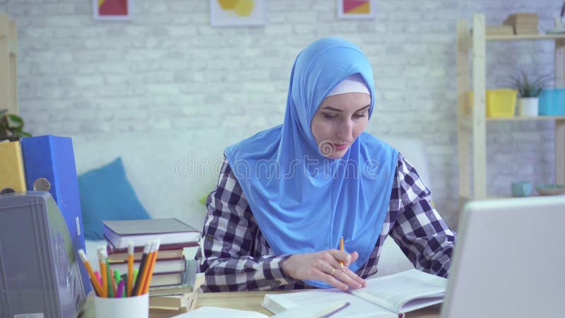 Όμορφη νέα μουσουλμανική γυναίκα στο hijab, που μελετά στο σύγχρονο πορτρέτο διαμερισμάτων